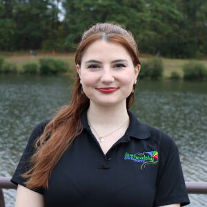 Smiling redheaded woman by lakeside wearing polo