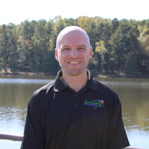 Smiling man by lake with wooded background