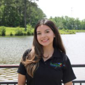 Smiling young woman standing by lakeside railing
