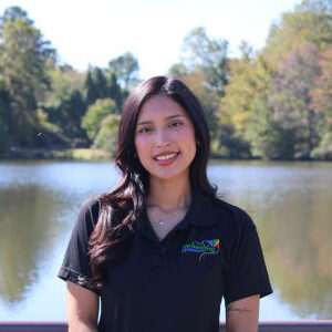 Woman smiling by lakeside wearing black polo