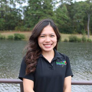 Smiling woman in black polo by lake