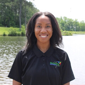 Smiling woman in black polo by lake