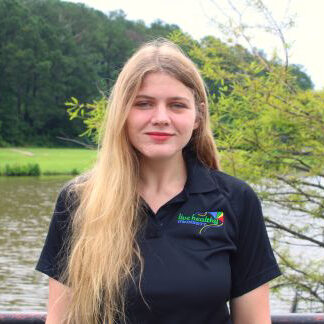 Person with long blonde hair by lake